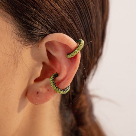 De groene rhinestone oorclipvariant gedragen aan een oor, die zijn briljante tint toont.