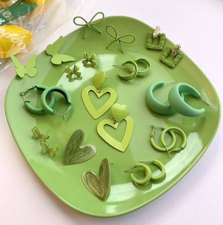 An artistic display of the green enamel earring collection on a heart-shaped plate.