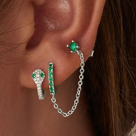 Een close-up van de oorbelset met levendige groene en heldere cubic zirconia edelstenen op een witte achtergrond.