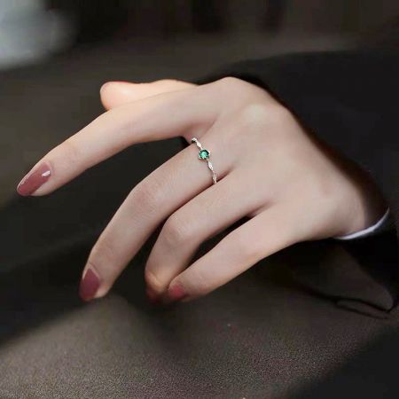 A hand model showcasing the beautiful green gemstone ring set.