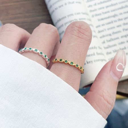 Close-up of the sterling silver and gold-plated green zircon stacking rings on a model's hand.