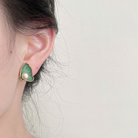 Detailed close-up of a green enamel and gold scallop pearl stud earring.