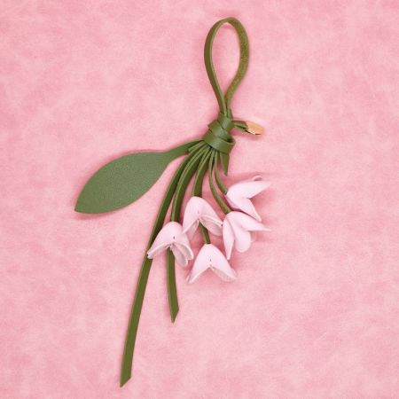 Porte-clés en cuir PU rose clair en forme de fleur avec un cordon en cuir vert, parfait pour les sacs à main.