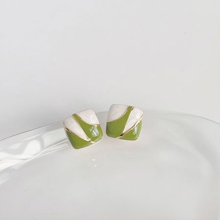 Vue rapprochée des boucles d'oreilles en style céramique vert et blanc avec des bordures dorées.