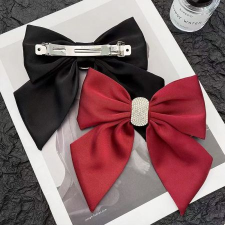 Una disposición elegante de los lazos para el cabello rojos y negros junto a una botella de perfume, destacando su atractivo de moda.