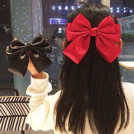 Wholesale Girls' Vintage Bowknot Hair Alligator Clip for Ponytail (5 pcs) - A model showcasing the vintage-style bowknot hair alligator clip, wearing a red bow in her ponytail and holding a black one.