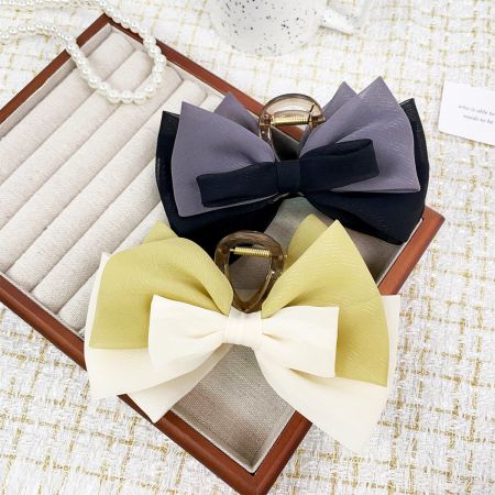 A collection of colorful fabric bow hair clips displayed on a jewelry box.