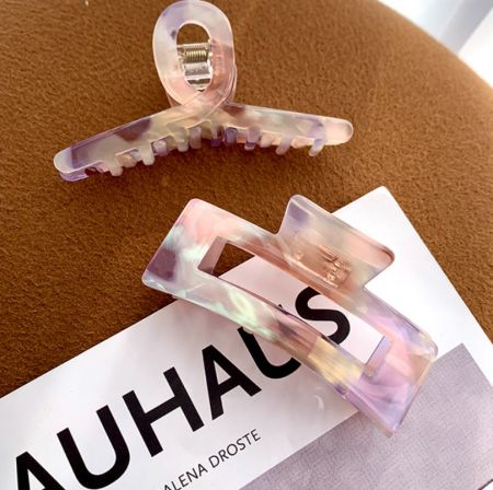 Una collezione di eleganti fermagli per capelli in acetato esposti con una scheda del marchio JR Fashion Accessories.