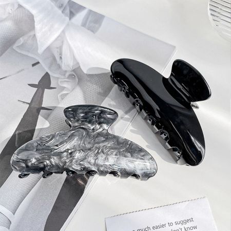 A classic black and a textured silver claw hair clip side by side.