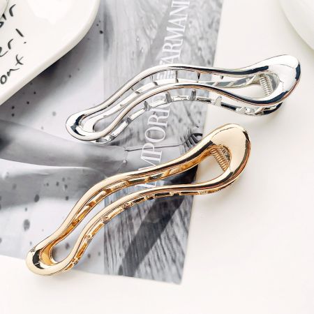 Primer plano de elegantes clips de pelo de metal con diseño ondulado en oro y plata.