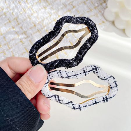 Two fabric-covered hair clips, one black with white speckles and one white with black speckles.
