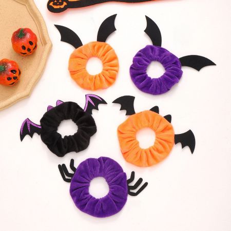 Três scrunchies de Halloween com asas de morcego nas cores laranja, roxa e preta.