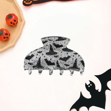 Eine schwarze Halloween-Haarklammer mit Designs von Fledermäusen, Hexenhüten und Sternen.
