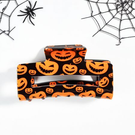 Een feloranje jack-o'-lantern klauwenclip, die een feestelijke touch aan elke look toevoegt.