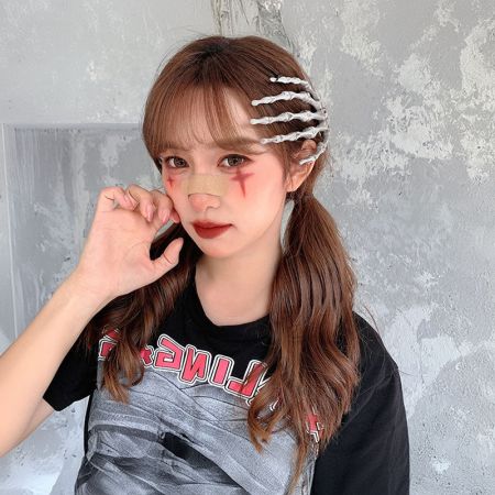 Modelo con maquillaje dramático de calavera de Halloween que lleva el clip de mano esqueleto para completar el look.