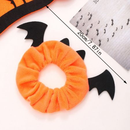 Close-up de um scrunchie laranja de Halloween com asas de morcego pretas.