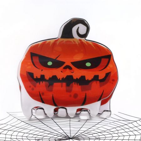 A pumpkin-shaped hair clip with a skull face for Halloween.
