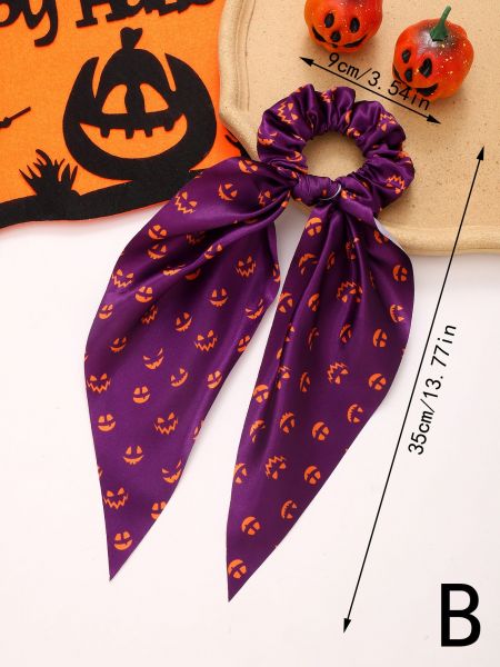 Close-up van een paarse Halloween scrunchie met een jack-o'-lantern patroon en lintstaarten.