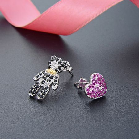 Primo piano di un ciondolo a forma di mano e di un orecchino a perno a forma di cuore rosa della collezione in argento sterling 925.