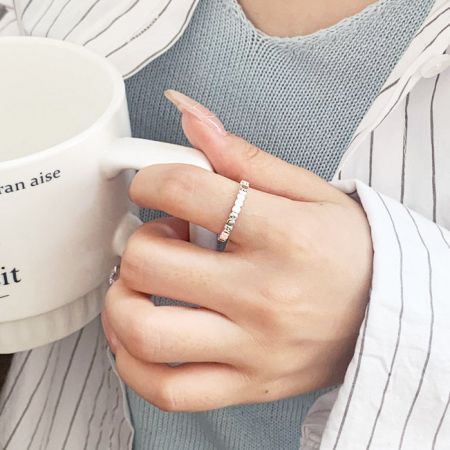 A lifestyle image showing the silver square brick design ring being worn while holding a mug.