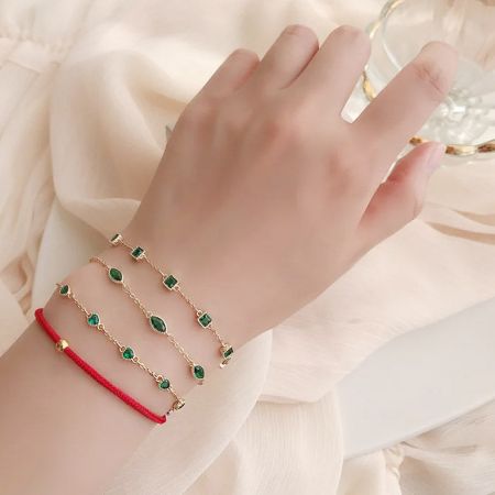Model's wrist adorned with a stack of stylish green gemstone and red cord bracelets.