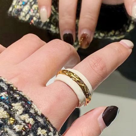 Close-up of a hand wearing two of the double-color enamel rings, highlighting their fit and style.