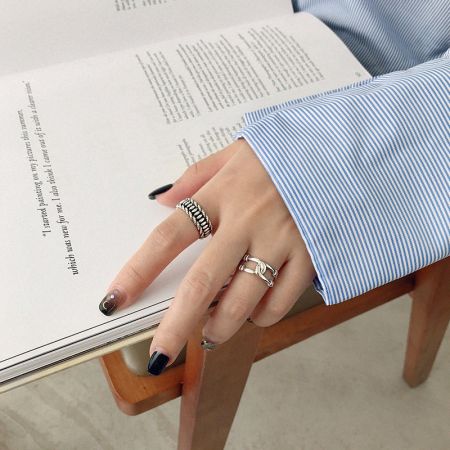 Close-up of a model's hand wearing the vintage-style sterling silver ring set, showcasing the assorted textures.