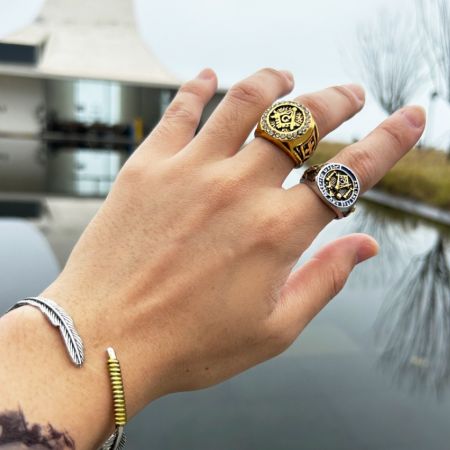 A collection of custom men's jewelry, including the Masonic ring, worn on a hand to showcase its style.