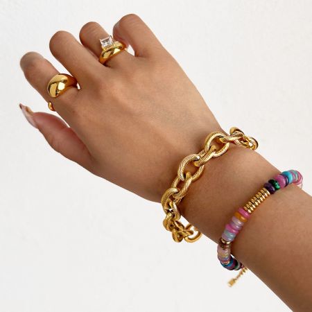 Een gestileerde lifestylefoto van een hand versierd met de complete set van vijf armbanden in goudtint, die een gestapeld uiterlijk demonstreert.