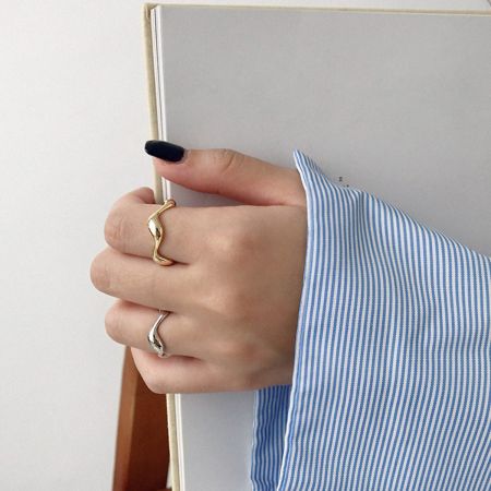 Een close-up van de golvende verstelbare ringen op een hand, die hun elegante ontwerp voor dagelijks gebruik toont.