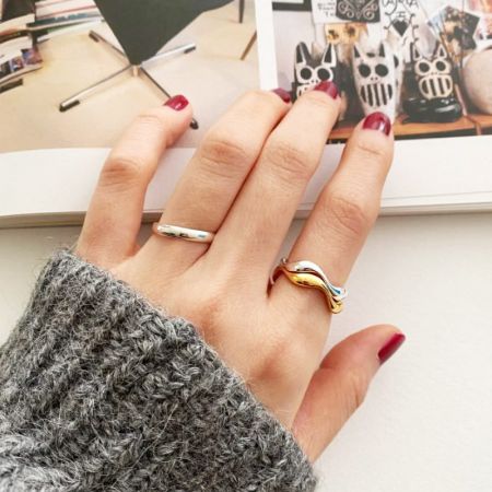 De hand van een model die de stapelbare golvende ringen draagt, en laat zien hoe ze gestyled kunnen worden.