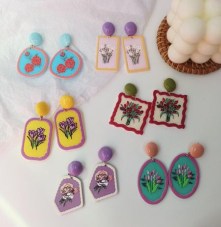 Una colección de pendientes de acrílico florales hechos a mano en varias formas y colores vibrantes.