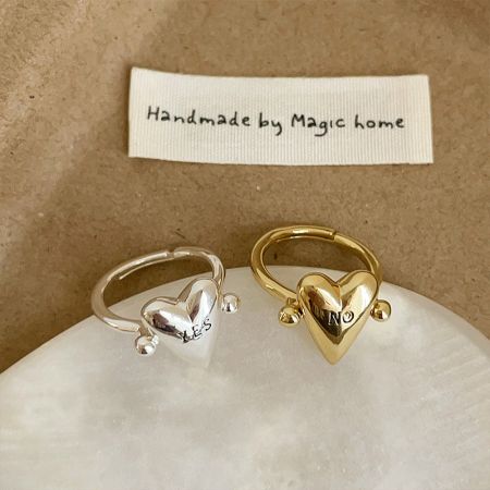 Detailed view of a gold-plated adjustable brass ring with a heart motif and 'NO' engraving.