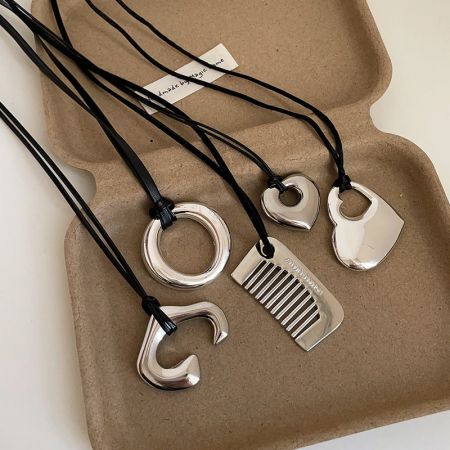 Assortment of minimalist brass pendants including comb, heart, and round shapes.