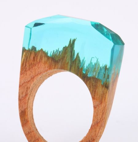 Primer plano de un anillo de madera hecho a mano con un vibrante incrustación de piedra turquesa.