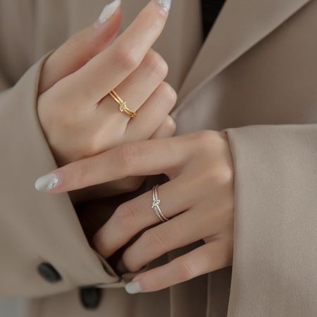 Un modello che indossa l'anello a nodo placcato in oro insieme a un anello d'argento per mostrare il suo stile versatile.