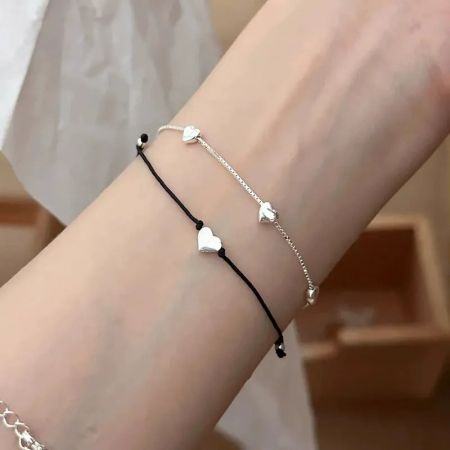 925 Sterling Zilveren Minimalistische Hartarmbanden voor Vriendin - Een set van minimalistische hartarmbanden van 925 sterling zilver elegant gedragen om een pols, die hun delicate en stapelbare ontwerp toont.