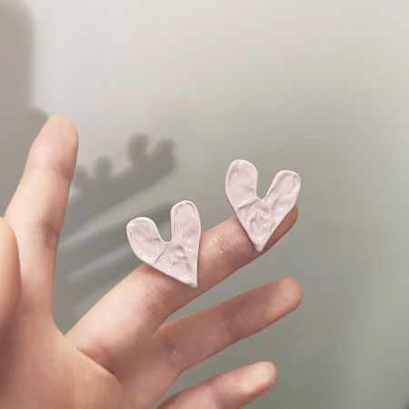 Boucles d'oreilles en forme de cœur martelé rose en gros (5 paires) - Une paire de boucles d'oreilles en forme de cœur en émail rose en gros avec une texture martelée, présentée sur un fond blanc.