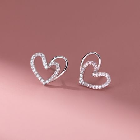 Een paar zilveren hartvormige stud oorbellen bezet met kleine cubic zirconia stenen.