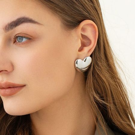 A model showcasing the chunky heart stud earring in gold.