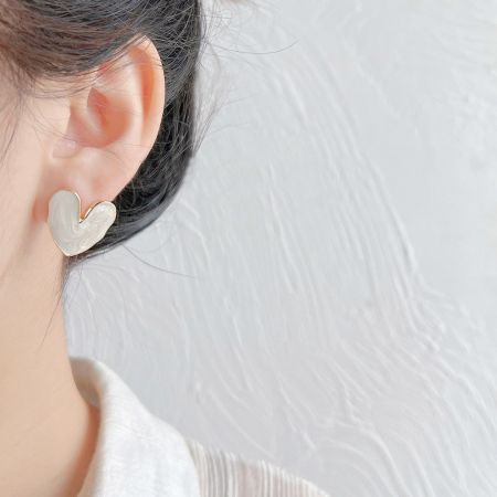 Model wearing the sweet white enamel heart stud earring to show scale and style.