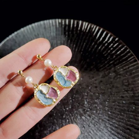 パールでアクセントを付けた金のカラフルなパズルデザインの魅力的なハート型イヤリング。