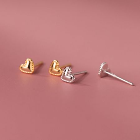 Un paio di orecchini a forma di cuore in finiture oro e argento esposti affiancati.