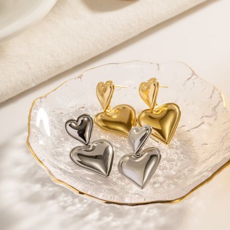 Gold and silver heart earrings displayed in a clear glass dish.