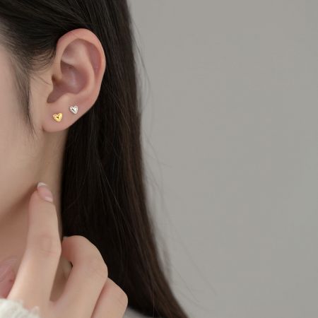 Modello che mostra il delicato orecchino a perno a forma di cuore in argento sterling 925.