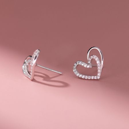 Gedetailleerd uitzicht op de zilveren holle hart stud oorbellen met diamanten details.