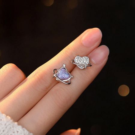 Een hand die de delicate hartvormige sterling zilveren oorbellen vasthoudt.