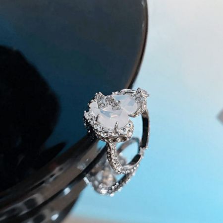 Un delicado anillo de plata con una piedra preciosa en forma de corazón.