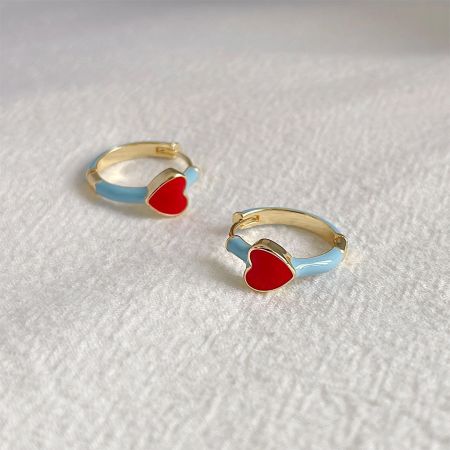 Prise de vue détaillée des boucles d'oreilles en or en forme de cœur avec émail coloré.