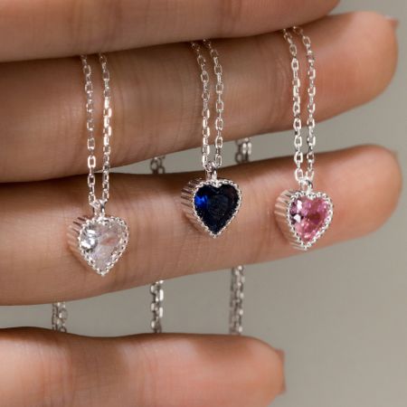 Juego de collares de corazón de plata esterlina 925 con colgantes CZ Pave. - Una colección de tres collares de corazón de plata esterlina 925 con piedras preciosas CZ transparentes, azules y rosas, exhibidos sobre un fondo blanco.